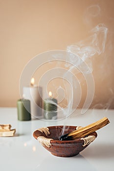 Palo santo burning stick and candles in background