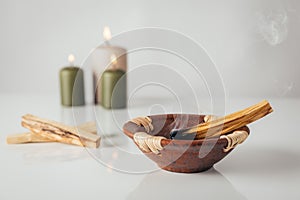 Palo santo burning stick with candles in background