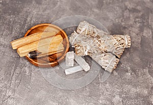 Palo Santo sticks, dried white sage, crystals on a grey background.