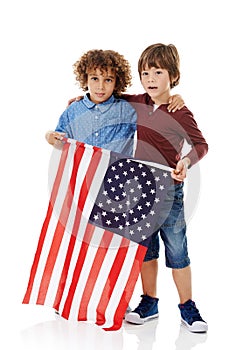 Pals in patriotism. Studio shot of two cute little boys holding the American flag together against a white background.