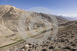 Pamir Highway in the desert landscape of the Pamir Mountains in Tajikistan. Afghanistan is on the left