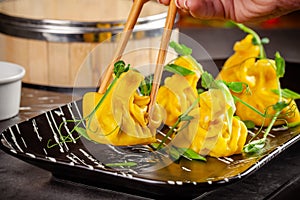 Pan-Asian cuisine concept. Wontons of yellow dough, minced meat. Japanese dumplings with minced meat. Serving dishes