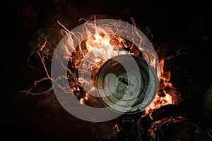 Pan with a cover standing on the bonfire in the night