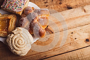 Pan de muerto, concha and other sweet breads on wooden table.