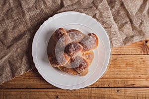 Pan de muerto on a white plate isolated on a wooden table.