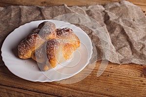 Pan de muerto on a white plate isolated on a wooden table.