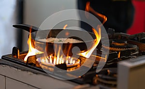 Pan of food sizzling on a gas hob