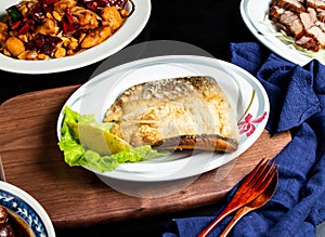 Pan fried fish maw with lemon, spoon and fork served in dish isolated on wooden board side view of taiwan food photo
