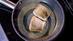 Pan-fried fish, Two pieces of loban fillet on the steaming frying pan. photo