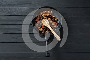 Pan of fried mushrooms champignons on a dark wooden background. Top view. Place for text and copy space. Mushrooms are