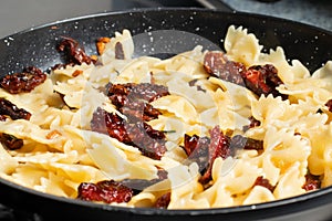 Pan-fried pasta with sun-dried tomatoes and garlic. Stages of cooking Italian cuisine