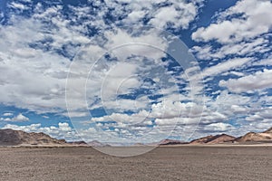 Pan of the Namibia desert with mountains and cloudy sky.