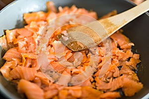 Pan with Pile of Cut Salmon Pieces, on stove. with wooden spoon