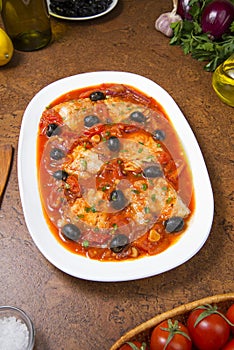 Pan seared fish with tomatoes and olives. Selected focus.