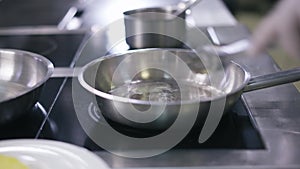 Pan on stove with male hand in glove melting butter close-up. Unrecognizable man preparing kitchenware cooking in