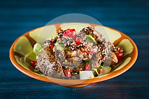 Pan of traditional Japanese yakitori dish - fried checken hearts served with sesame, teriyaki sauce and fresh vegetables at wooden