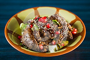 Pan of traditional Japanese yakitori dish - fried checken hearts served with sesame, teriyaki sauce and fresh vegetables at wooden