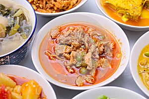 Panaeng Curry with Pork.Sliced M in red curry paste and coconut milk in a bowl on the set of group plates Thai food. Top view.