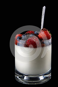 Panakota creamy Italian dessert in a glass cup with berries and a spoon