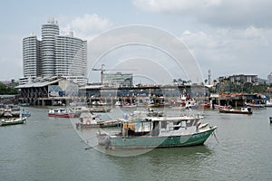 Fishing boats at commercial fish market harbour with skyline bac