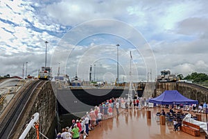 A cruise ship with the passengers on the bow watching a the water being raise  on the first lock in the Panama Canal