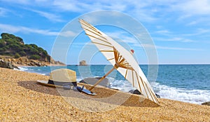 Panama hat and beach umbrella on the sandy beach near the sea. Summer holiday and vacation concept for tourism photo