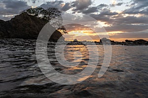 Sunset beach on high tide with rock photo