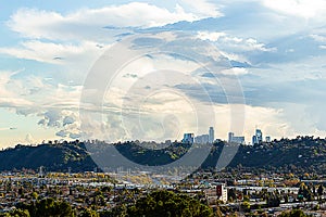 Panaramic view of city businesses and homes with hillside homes and downtown LA towers in the distance