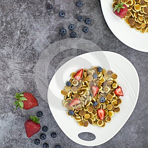 Pancake cereal. Trendy food, mini cereal pancakes in bowl on the table, grey cement background. Trendy baked mini