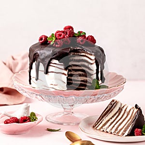 Pancake chocolate cake with fresh raspberries on a pink background.
