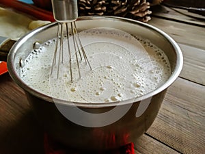 The pancake dough is mixed with a whisk. Corolla in the dough. cooked pancakes - eidy dough with a whisk for mixing.