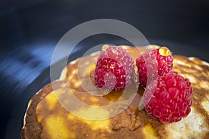 Pancake with fresh raspberries and honey on a dark background. Gramophone record. View from above. Closeup. Food, breakfast