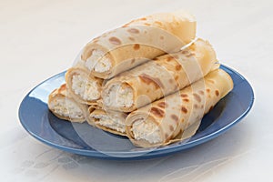 Pancake rolls with cottage cheese on blue plate.