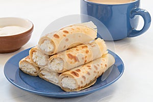 Pancake rolls with cottage cheese on blue plate.