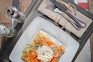 Pancake with salmon and sourcream and dille on a white plate.