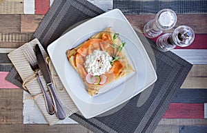 Pancake with salmon and sourcream and dille on a white plate.