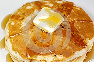 Pancake with a square of butter and syrup on a kitchen table waiting to be eaten