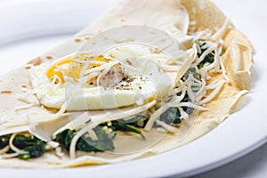 pancake stuffed with spinach leaves served with fried egg and grated cheese