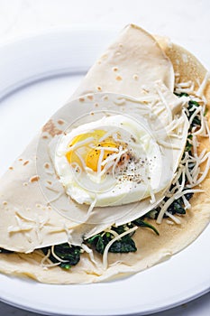 pancake stuffed with spinach leaves served with fried egg and grated cheese