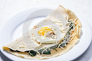 pancake stuffed with spinach leaves served with fried egg and grated cheese