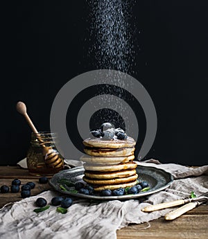 Pancake tower with fresh blueberry and mint on a rustic metal plate.