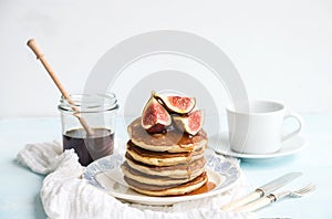 Pancake tower with fresh figs and honey on a rustic plate. White background