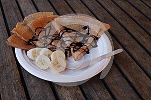 Pancakes with banana on a chinet disposable paper plate and wooden disposable  cuttlery