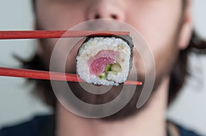 Pancakes from cast iron discs on white plate black tableHand using chopsticks pick. Maki-Sushi, tuna-maki r