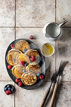 Pancakes in ceramic plate with berries and forks, top view