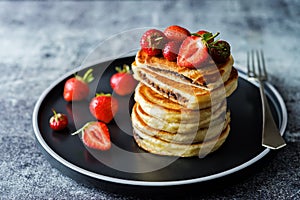 Pancakes with chocolate nutella filling decorated with strawberries