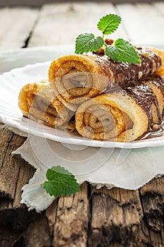 Pancakes with chocolate, nuts and mint leaf on an old wooden tab