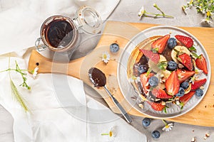 Pancakes with chocolate paste and hazelnuts, banana, strawberry and blueberry