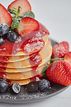 Pancakes close up, with fresh strawberry, blueberries, mint and jam