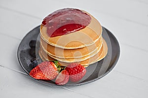 Pancakes close up, with fresh strawberry, blueberries, mint and jam